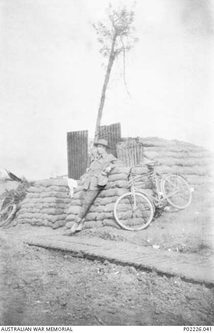 Ypes, France. 1917-09-26. Lieutenant (Lt) Wal Higgins, No. 1 Field Company, Royal Australian Engineers, leans against the wall of the dugout he shared with Lt Cyril Lawrence. Note the bicycles leaning against the sand bags and the sheets of galvanised iro