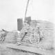 Ypes, France. 1917-09-26. Lieutenant (Lt) Wal Higgins, No. 1 Field Company, Royal Australian Engineers, leans against the wall of the dugout he shared with Lt Cyril Lawrence. Note the bicycles leaning against the sand bags and the sheets of galvanised iro